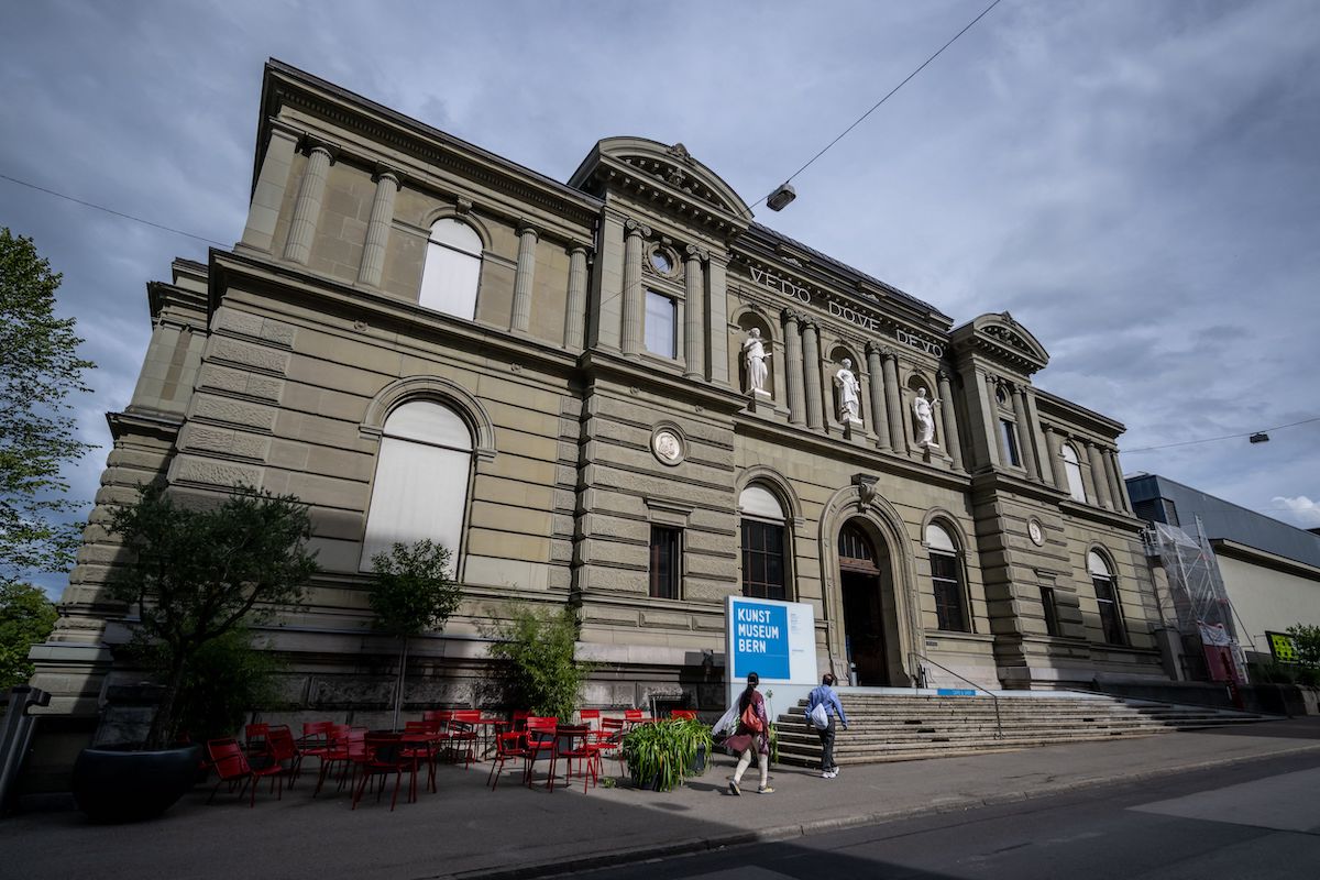 A museum facade with people walking up its steps.