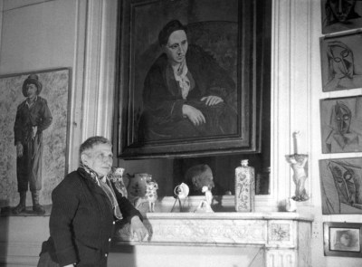 Gertrude Stein poses in front of Picasso's 1906 portrait of her in her Paris apartment, n.d.