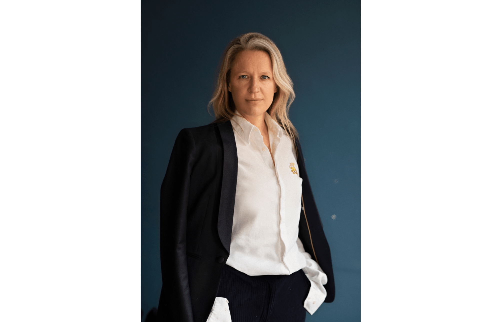 A blonde woman in a white shirt and black suit.